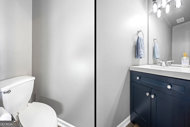 bathroom featuring toilet, vanity, baseboards, and ornamental molding