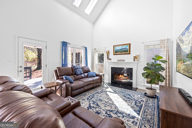 living room with a skylight, a high end fireplace, and high vaulted ceiling