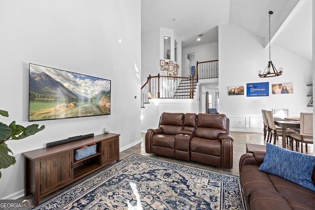 living room featuring stairway, high vaulted ceiling, and an inviting chandelier