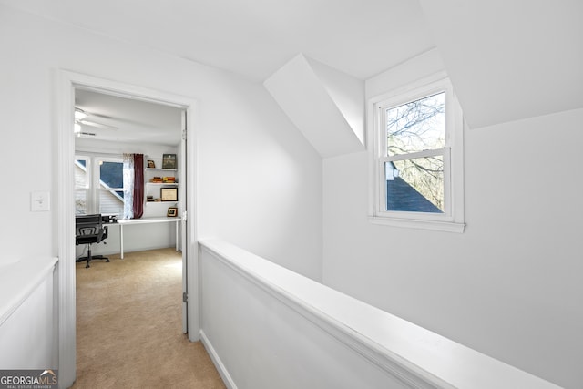 corridor featuring light colored carpet and lofted ceiling