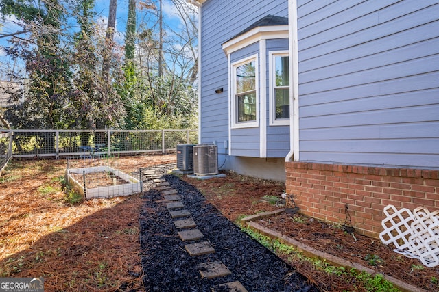 view of yard with a vegetable garden, central AC, and fence