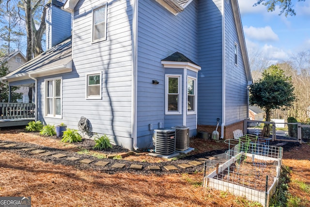 view of property exterior featuring central air condition unit and a vegetable garden