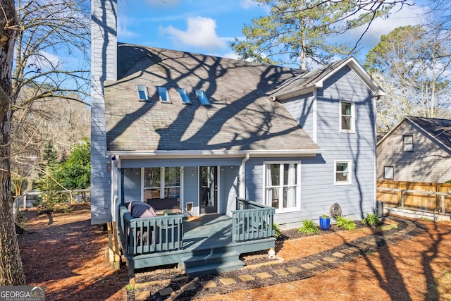 rear view of house featuring crawl space, a shingled roof, and fence