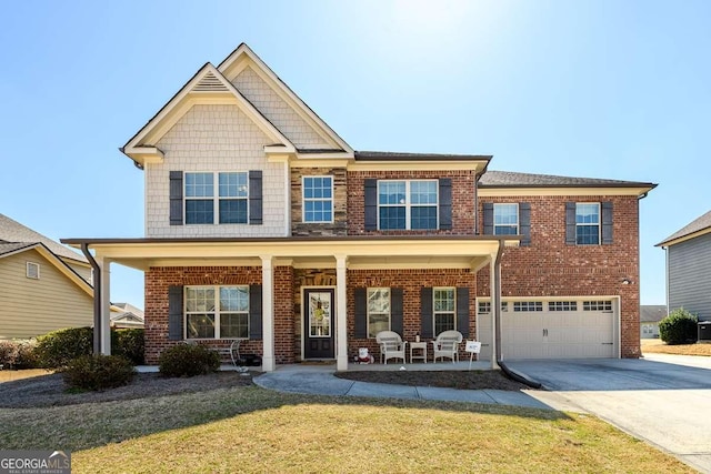 craftsman house with a front yard, a porch, an attached garage, concrete driveway, and brick siding