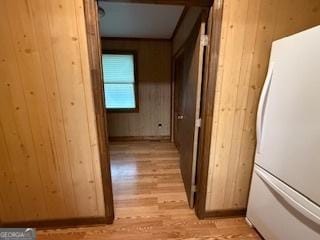 hallway with light wood finished floors and wooden walls