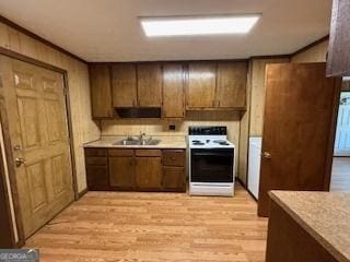 kitchen with a sink, light countertops, light wood finished floors, and white electric stove