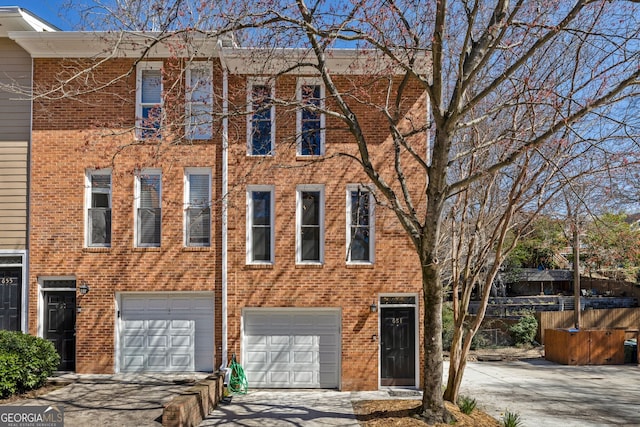 view of property with a garage, brick siding, and driveway