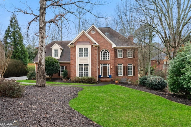 view of front of house with a front yard, brick siding, and a chimney