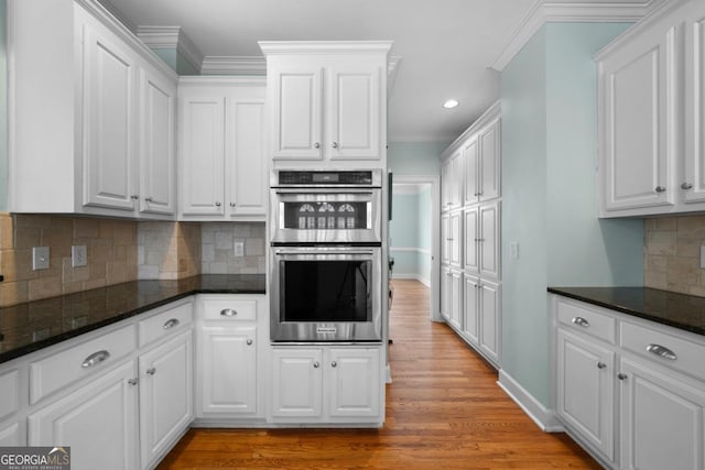 kitchen featuring light wood-style flooring, double oven, white cabinetry, and ornamental molding