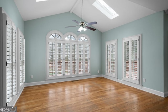 spare room with vaulted ceiling with skylight, baseboards, and wood finished floors