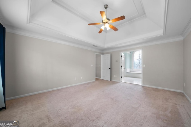 unfurnished bedroom featuring light carpet, a raised ceiling, connected bathroom, crown molding, and baseboards