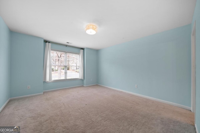 carpeted spare room featuring visible vents and baseboards