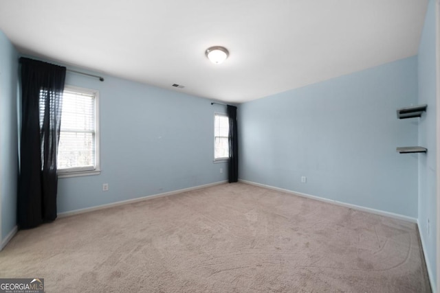 carpeted spare room featuring visible vents and baseboards