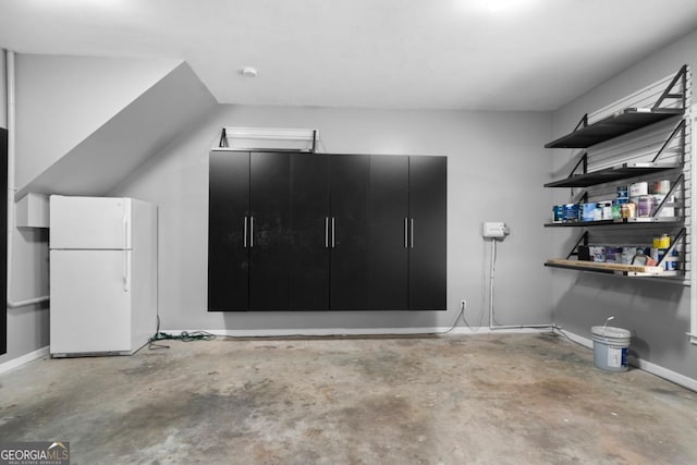 garage with baseboards and freestanding refrigerator