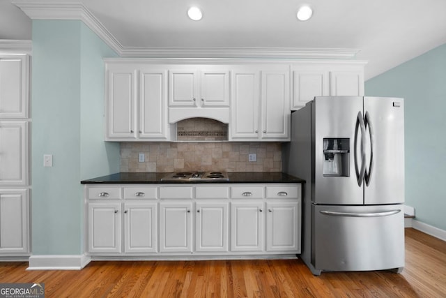 kitchen with stovetop, backsplash, white cabinets, and stainless steel fridge with ice dispenser