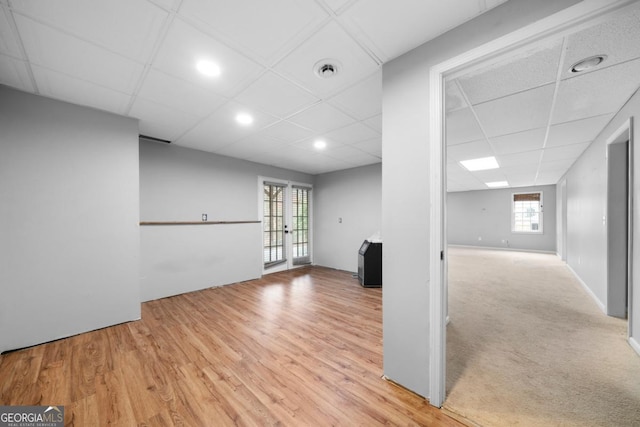 unfurnished room with a drop ceiling, french doors, light wood-style floors, and visible vents