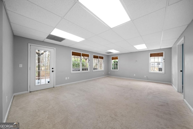 empty room with a drop ceiling, baseboards, and carpet floors