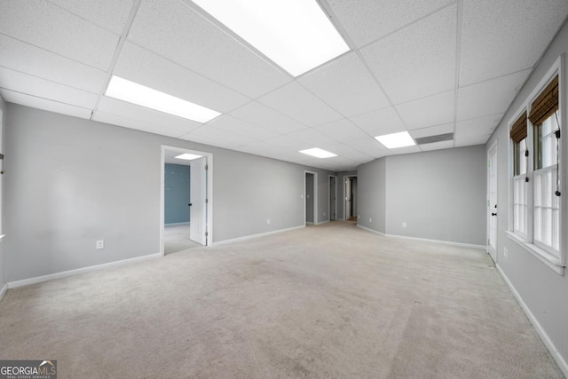 carpeted empty room with a paneled ceiling and baseboards