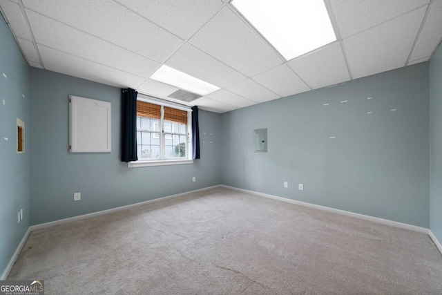 carpeted empty room with electric panel, a paneled ceiling, and baseboards