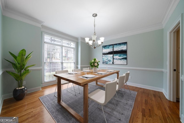 dining area featuring baseboards, a notable chandelier, wood finished floors, and crown molding