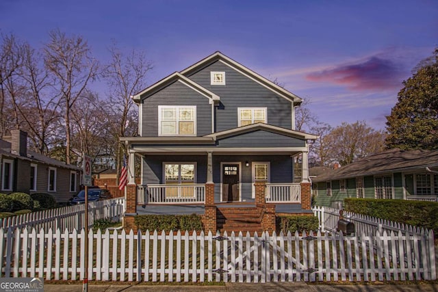 view of front facade featuring a fenced front yard, covered porch, and brick siding