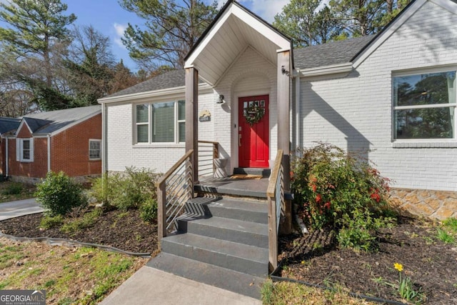 exterior space with brick siding and roof with shingles