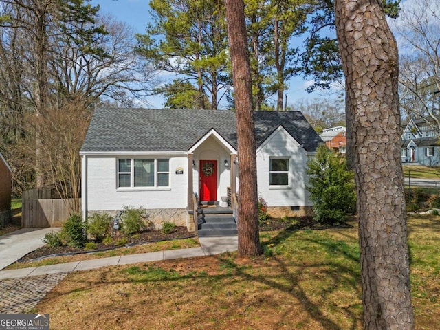 view of front of property featuring brick siding, fence, a front yard, roof with shingles, and crawl space