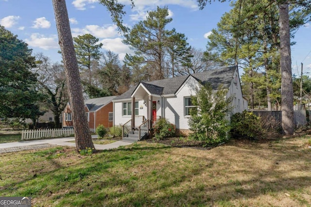 view of front of house with brick siding, a front yard, and fence