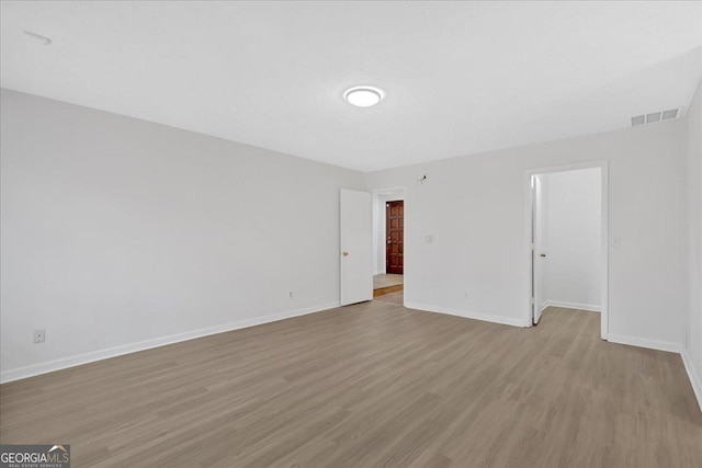 empty room featuring visible vents, baseboards, and wood finished floors