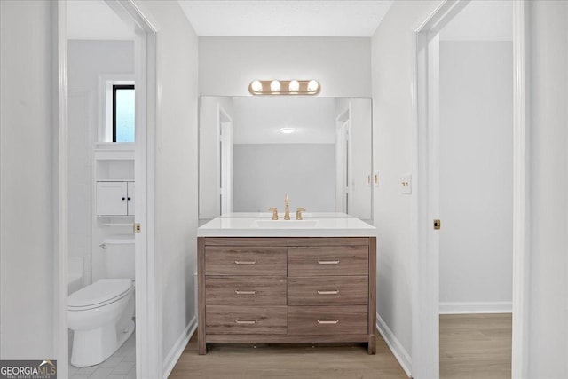 full bath with vanity, toilet, wood finished floors, and baseboards