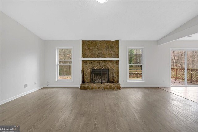 unfurnished living room with wood finished floors, a fireplace, baseboards, and vaulted ceiling