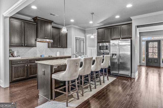 kitchen featuring visible vents, decorative backsplash, under cabinet range hood, appliances with stainless steel finishes, and crown molding