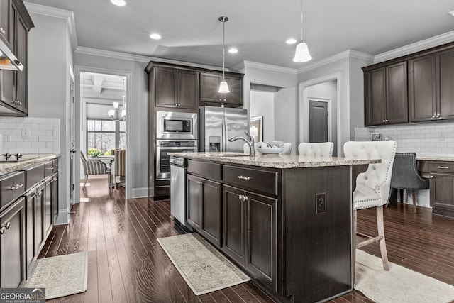 kitchen with appliances with stainless steel finishes, a kitchen bar, dark wood-type flooring, and crown molding