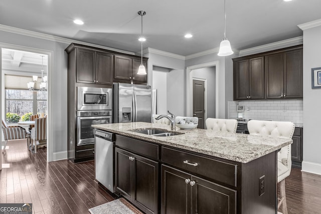 kitchen with dark wood finished floors, a sink, ornamental molding, stainless steel appliances, and tasteful backsplash