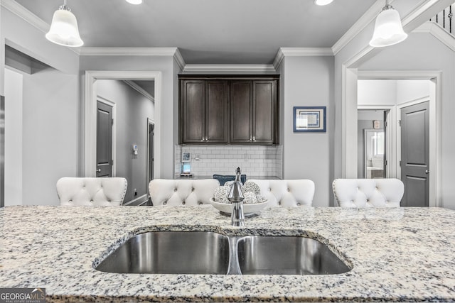 kitchen with dark brown cabinetry, light stone countertops, and pendant lighting