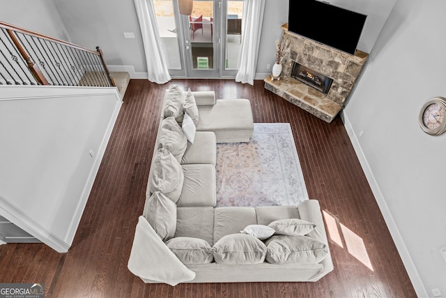 living area featuring baseboards, a fireplace, and stairs