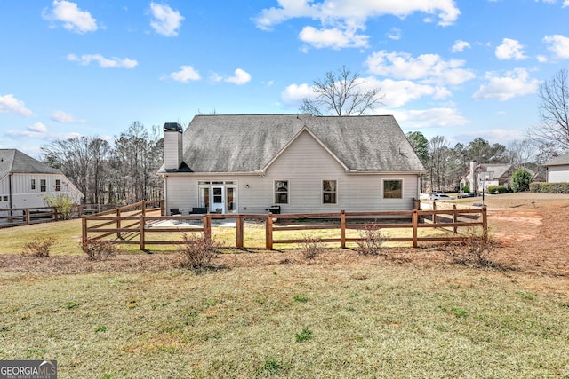 back of house with a yard, roof with shingles, a chimney, and fence