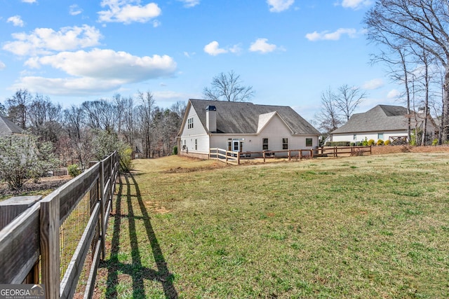 back of property with a yard, fence private yard, and roof with shingles