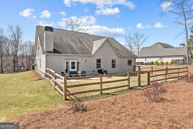 rear view of property with a lawn, fence private yard, a chimney, and a shingled roof