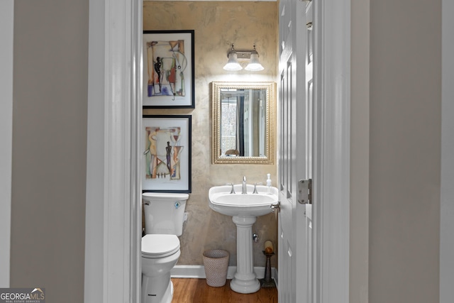 bathroom with toilet, baseboards, and wood finished floors