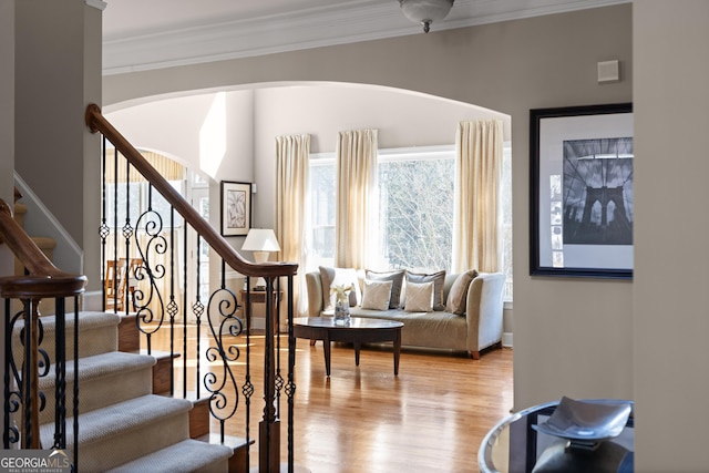 stairway with ornamental molding and wood finished floors