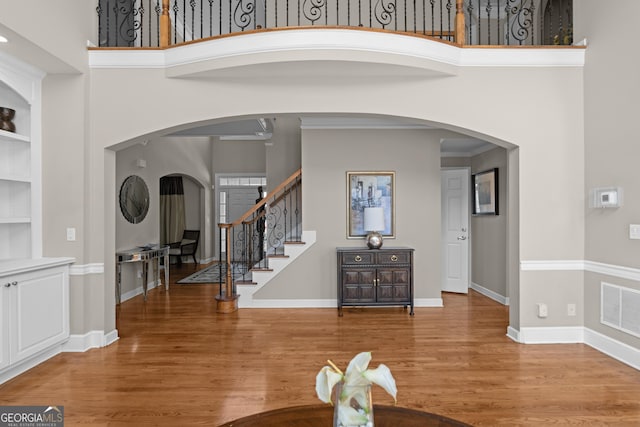 foyer with a high ceiling, baseboards, visible vents, and light wood finished floors