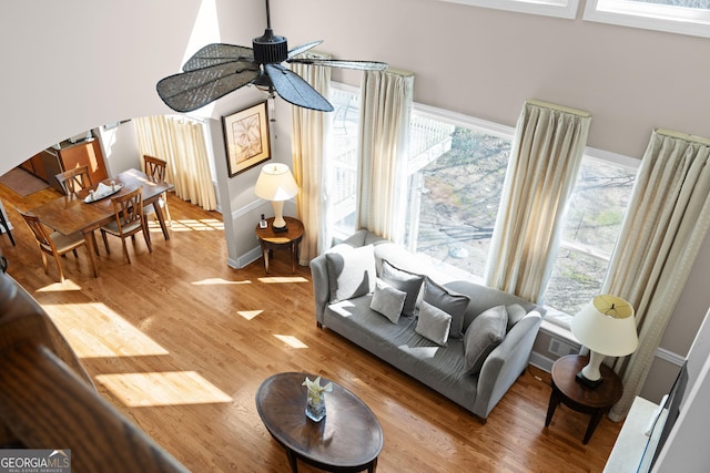 living room with light wood finished floors, a ceiling fan, and baseboards