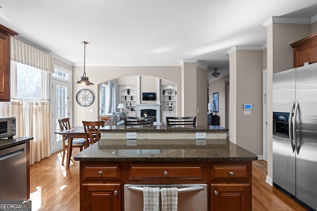 kitchen with crown molding, appliances with stainless steel finishes, a fireplace, and light wood finished floors