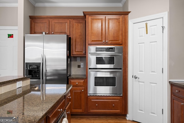 kitchen with ornamental molding, wood finished floors, brown cabinets, and stainless steel appliances