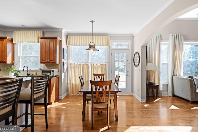 dining room with baseboards, light wood-type flooring, a wealth of natural light, and ornamental molding