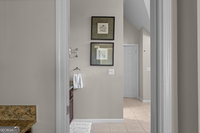 bathroom with tile patterned floors, vanity, baseboards, and vaulted ceiling