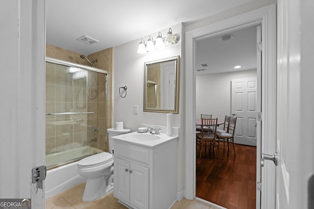 bathroom featuring visible vents, toilet, shower / bath combination with glass door, tile patterned flooring, and vanity