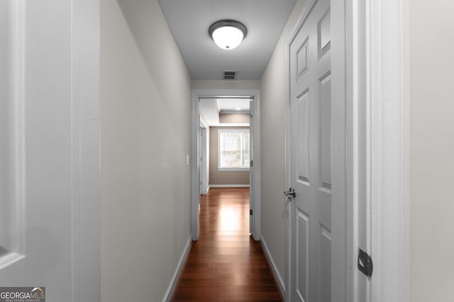 hall featuring dark wood finished floors, visible vents, and baseboards