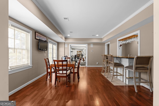 dining room with visible vents, crown molding, baseboards, and wood finished floors